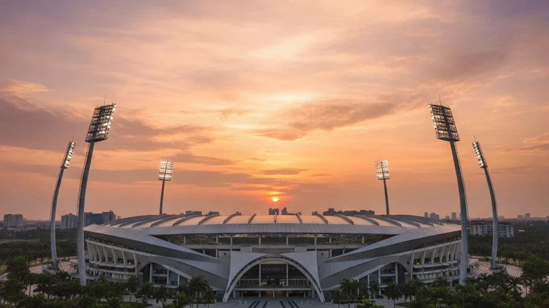 Football stadium with four floodlight pylons at golden-hour dusk